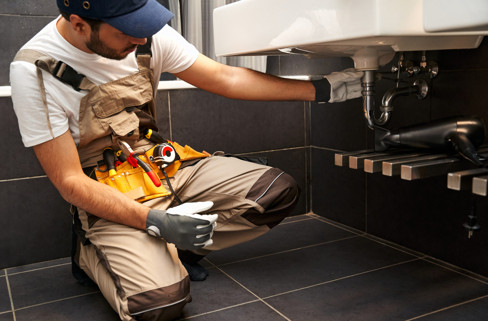 professional male plumber uniform is repairing bathroom sink home